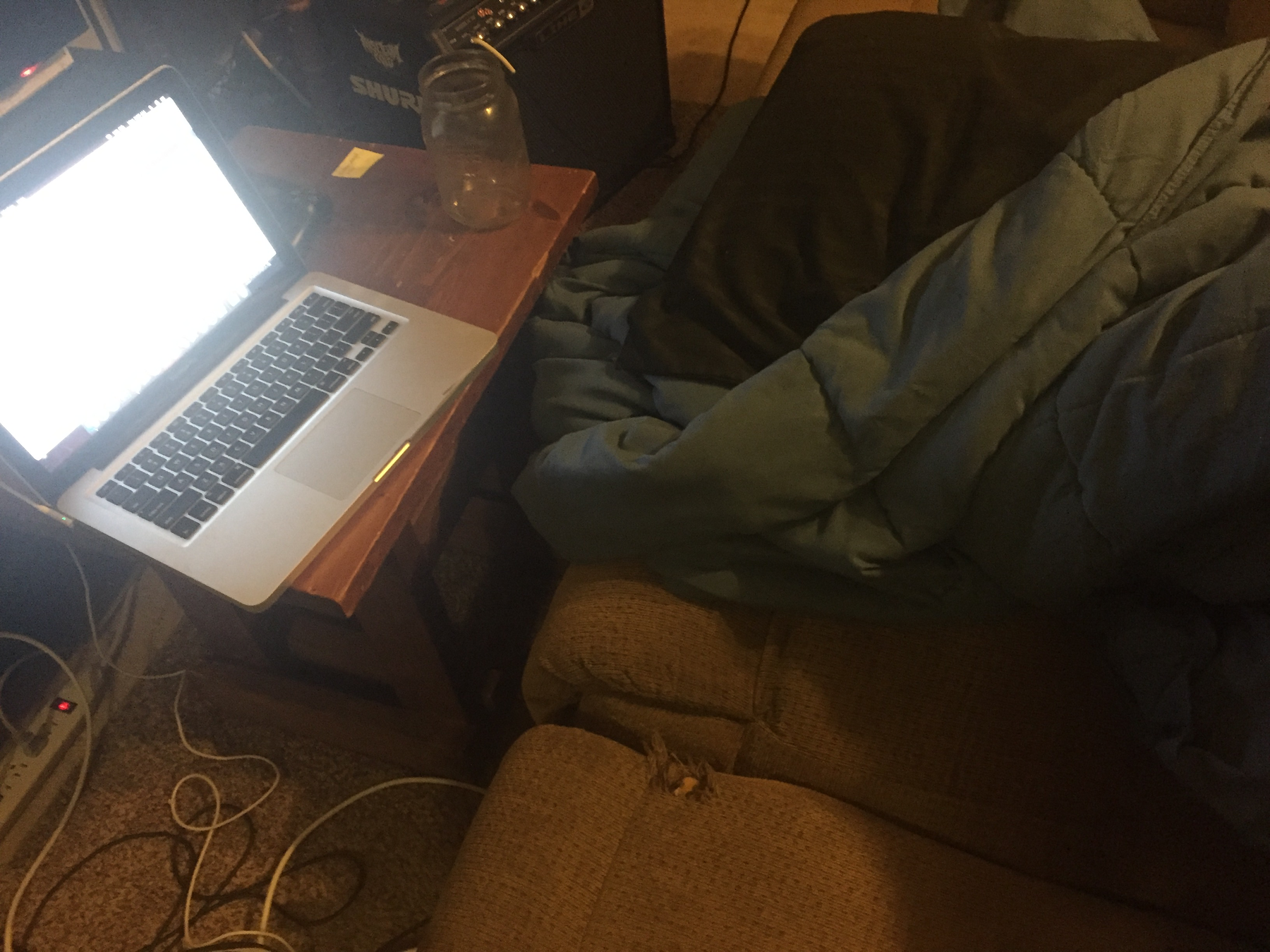 Computer on table next to sleeping bag and couch